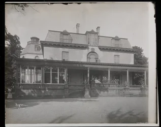 1907年、ニューヨーク州バリータウンのアスターチャンラー邸のポーチに立っている人々（銀ゼラチンプリント）